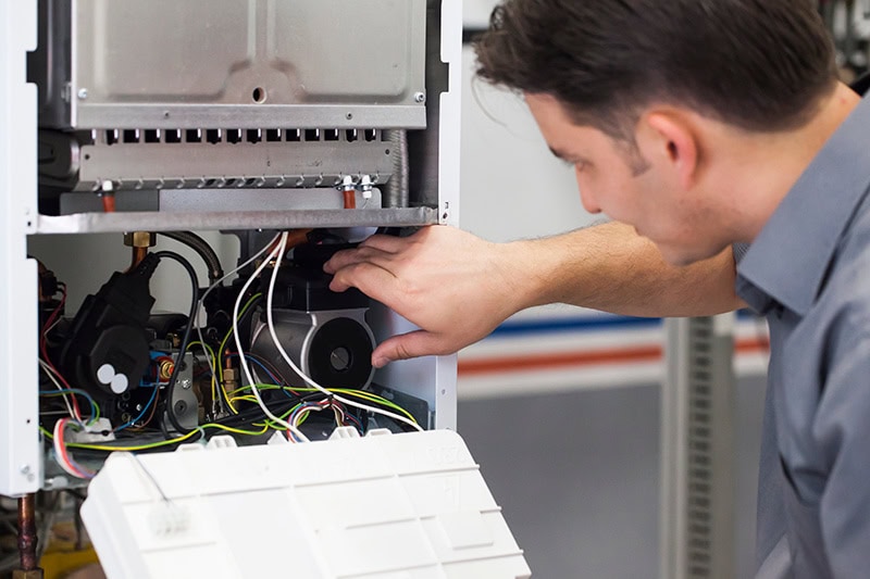 An HVAC technician performing maintenance on a heat pump system.